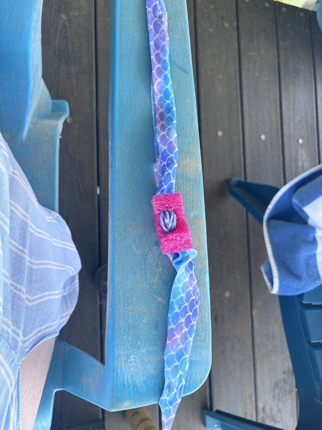Close-up of a pink Goggle Bean clipped to a colorful goggle strap on a blue chair
